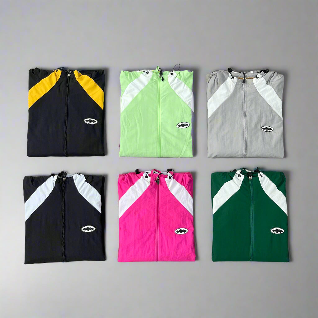 Six folded jackets in black, green, gray, pink, and green on a gray background